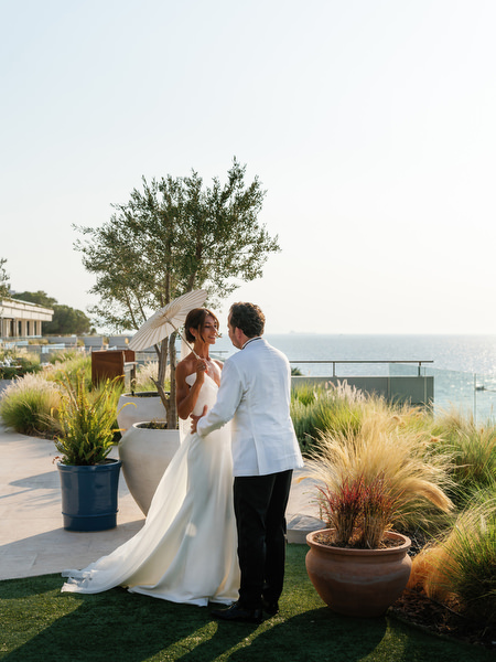Bride and groom sharing a quiet moment beside ornamental grasses at Vouliagmeni Lake