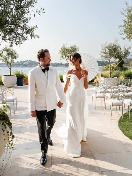 Bride and groom walking hand-in-hand across terrace at Four Seasons Athens during golden hour