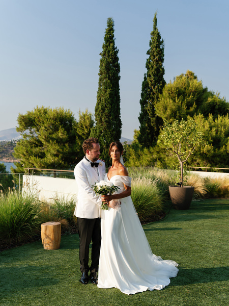 Bride and groom standing together on manicured lawn overlooking the Mediterranean Sea