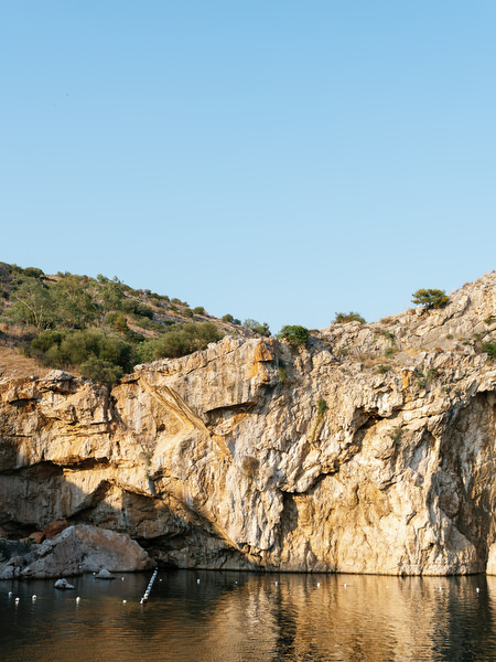 Dramatic rocky cliffs reflected in water at Vouliagmeni Lake during Athens destination wedding