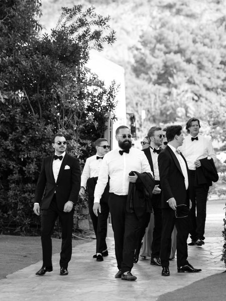 Group of groomsmen walking together in tuxedos during Athens Riviera destination wedding