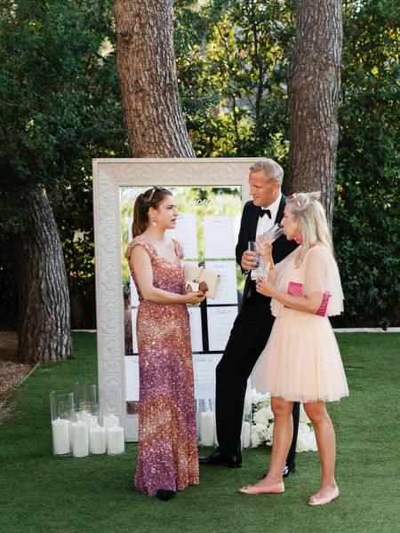 Wedding guests chatting beside framed seating chart and candle display