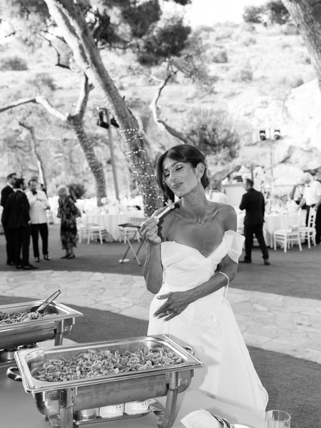 Bride serving herself from outdoor buffet station during relaxed lakeside reception