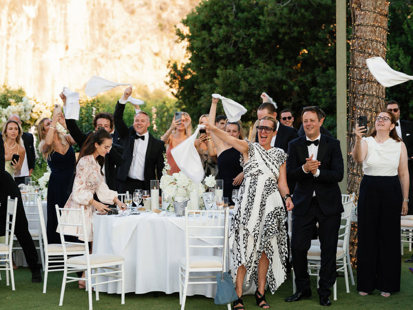 Friends cheering and raising napkins around candlelit reception tables