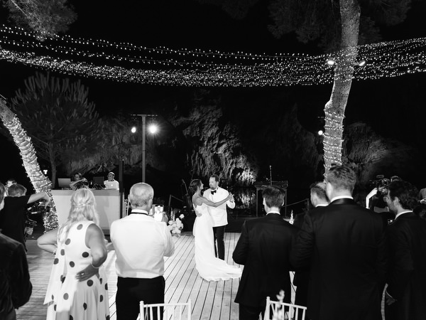 Bride and groom dancing beneath canopy of string lights at night reception