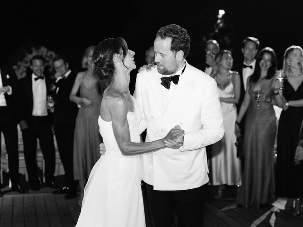 Bride and groom smiling at each other while dancing under string lights