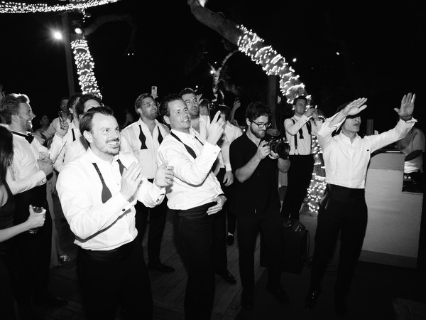 Wedding guests dancing and raising hands during lively summer party