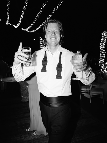 Smiling guest holding two drinks and celebrating on dance floor