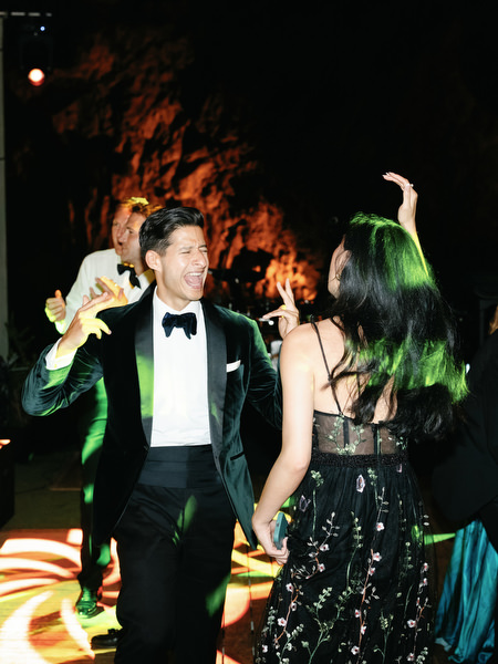Guests dancing under vibrant party lights at lakeside reception