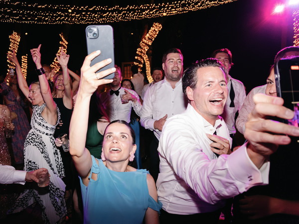 Group of guests taking selfie while cheering at lively wedding party