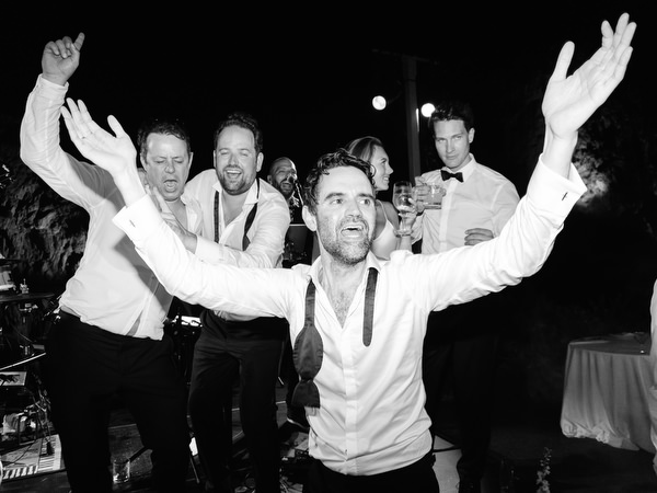 Wedding guests celebrating energetically beneath glowing string lights