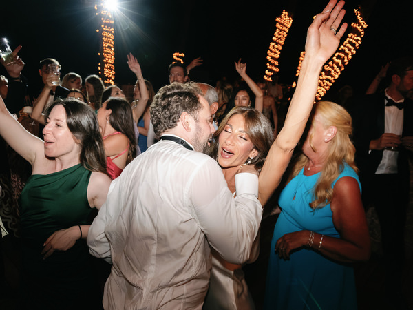 Guests dancing closely together under warm string lights at Athens black-tie wedding