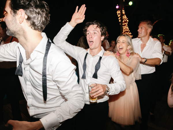 Guests dancing energetically with loosened bow ties during late-night reception