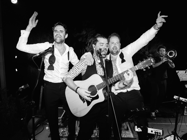 Wedding band performing as guests raise hands and sing along during unforgettable summer celebration