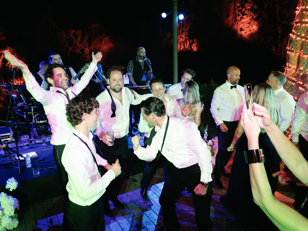 Group of guests jumping and cheering in front of live band at Vouliagmeni Lake reception
