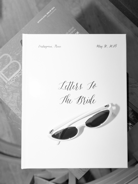 Black and white flat lay of “Letters To The Bride” book and white sunglasses during bridal preparations at Island Resort Athens Riviera