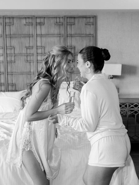 Bride sharing champagne with bridesmaid during getting ready at Divani Apollon Palace and Thalasso