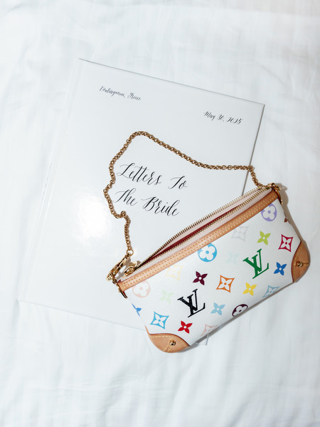 Flat lay detail of YSL bridal bag with letter to the bride on during bride’s wedding morning in Athens