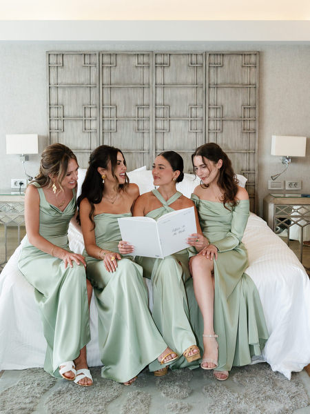 Bridesmaids in sage green dresses reading “Letters To The Bride” during Athens Riviera wedding preparations