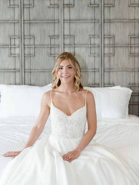 Bride seated on hotel bed in elegant wedding gown during luxury Athens Riviera bridal preparation