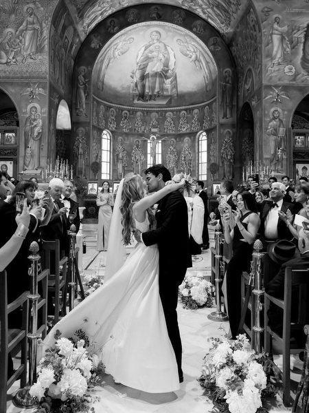 Bride and groom sharing their first kiss inside Greek Orthodox church in Athens