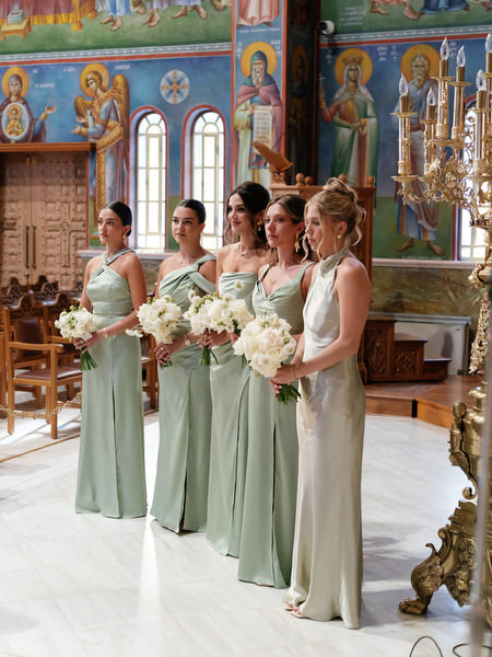 Bridesmaids in sage green gowns holding white bouquets during Greek Orthodox wedding in Athens