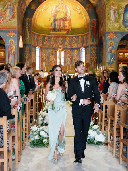 Bridesmaid and groomsman walking down aisle after Greek Orthodox ceremony in Athens