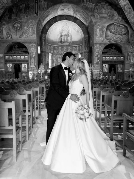 Bride and groom embracing inside Greek Orthodox church after ceremony in Athens