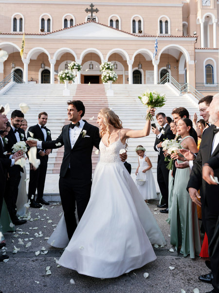 Bride and groom celebrating with guests outside Athens church after Greek Orthodox ceremony