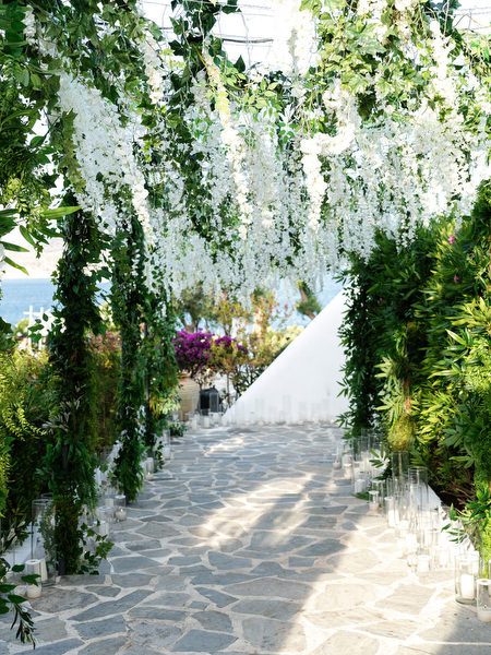 Lush greenery and cascading white florals forming reception tunnel at Island Resort Athens Riviera