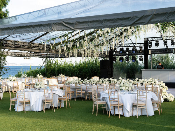 Full reception layout at Island Resort Athens Riviera with sea backdrop and overhead greenery installation