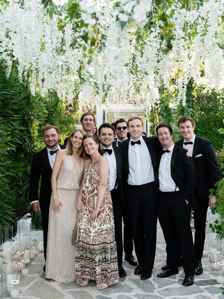 Wedding guests posing beneath cascading floral tunnel at Island Resort Athens Riviera reception
