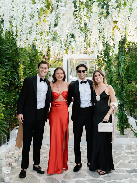 Elegant guests posing under hanging white florals during Island Resort Athens Riviera wedding