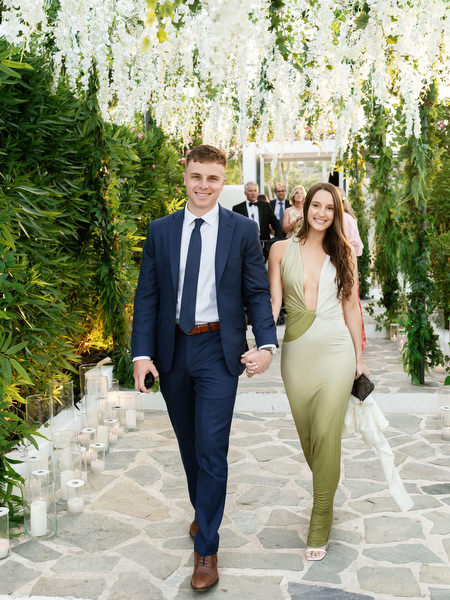 Wedding guests walking hand in hand through floral tunnel at Island Resort Athens Riviera
