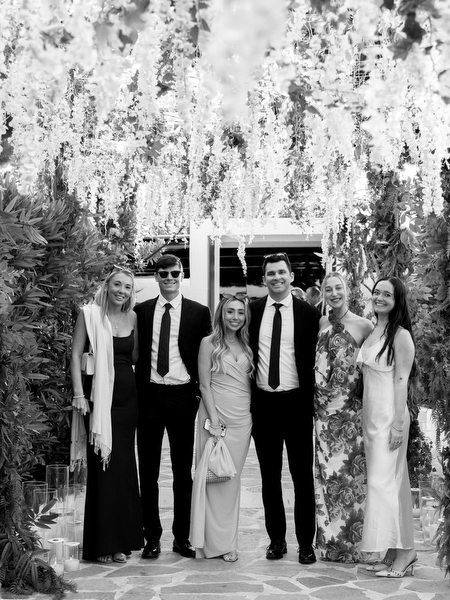 Group of guests posing under white floral tunnel during luxury Athens Riviera wedding