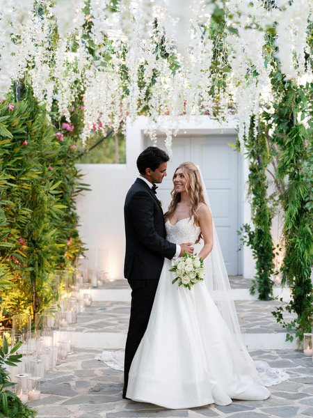 Bride and groom standing beneath cascading white florals at Island Resort Athens Riviera