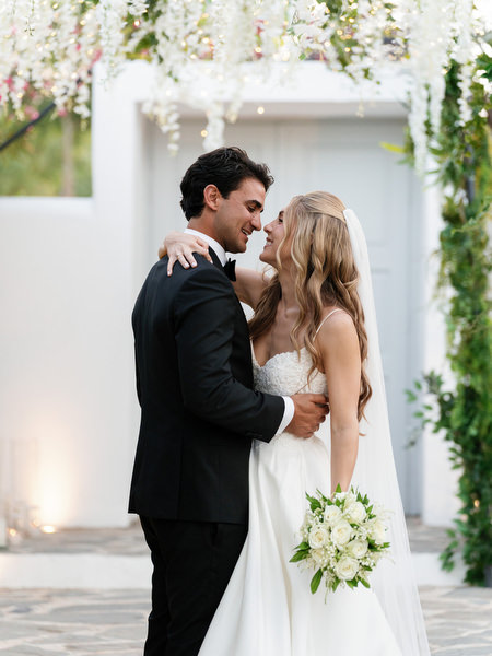 Bride and groom embracing under floral tunnel during luxury Island Resort Athens Riviera wedding