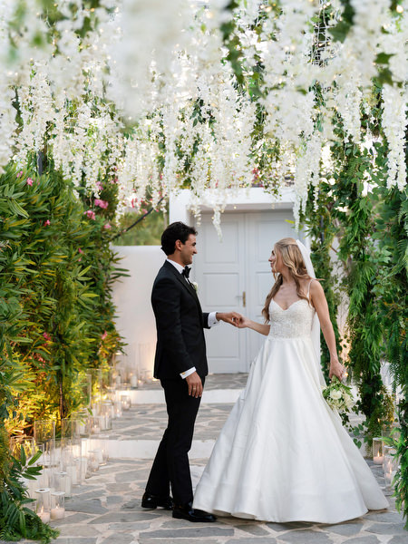 Bride and groom holding hands beneath greenery installation at Island Resort Athens Riviera