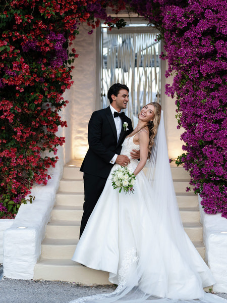 Bride and groom posing beneath vibrant bougainvillea during sunset portraits at Island Resort Athens Riviera