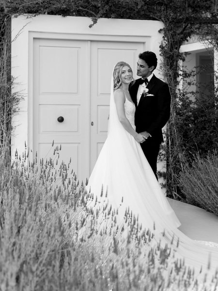 Bride and groom embracing outside white villa doors during Athens Riviera wedding