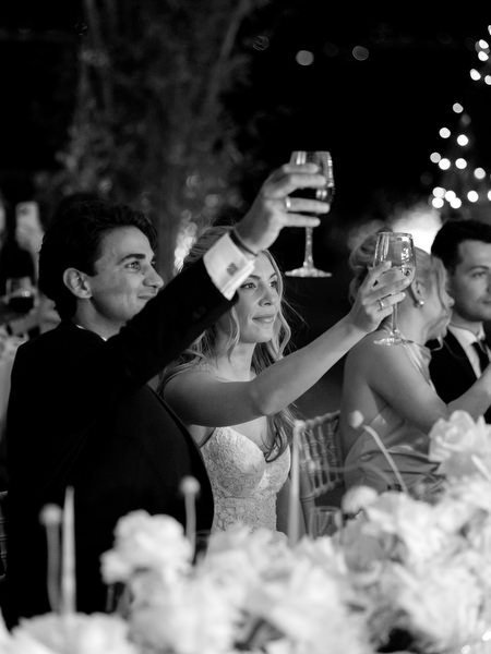 Bride and groom raising glasses during candlelit reception at Island Resort Athens Riviera