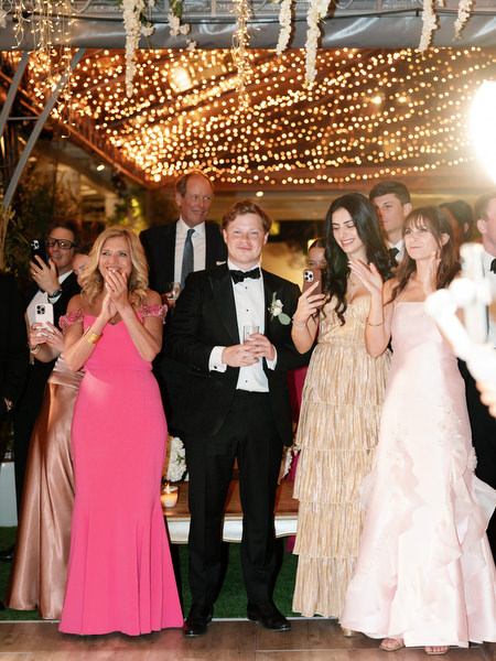 Guests clapping and smiling beneath string lights at Island Resort Athens Riviera