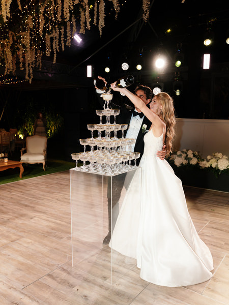 Bride and groom pouring champagne into tower during Island Resort Athens Riviera wedding reception