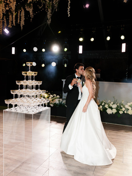 Bride and groom toasting beside champagne tower at Island Resort Athens Riviera