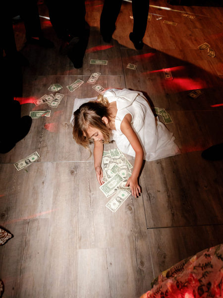 Young flower girl reaching for money during reception dance floor tradition at Island Resort Athens Riviera