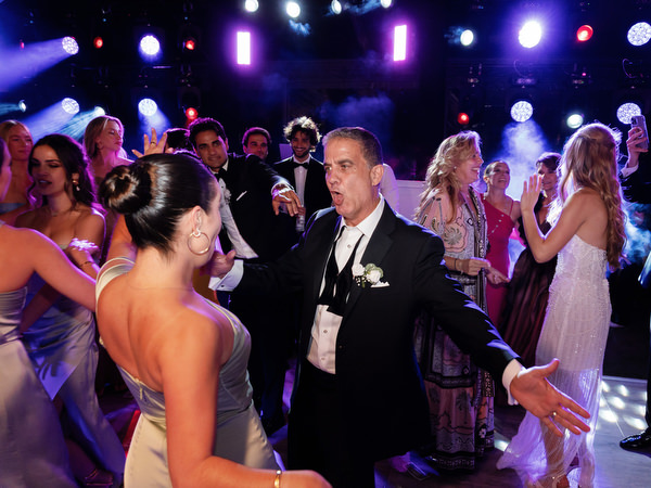 Guests dancing beneath colorful stage lighting at Athens Riviera wedding