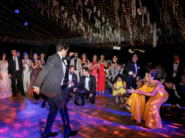 Groom performing dance move while guests form circle around him at Island Resort Athens Riviera