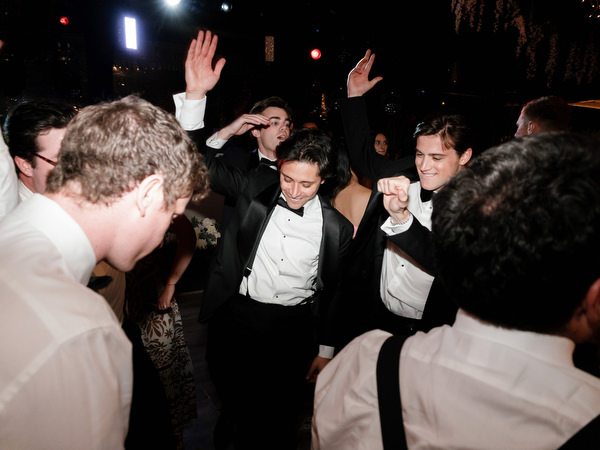 Group of groomsmen dancing together during energetic Athens Riviera wedding reception