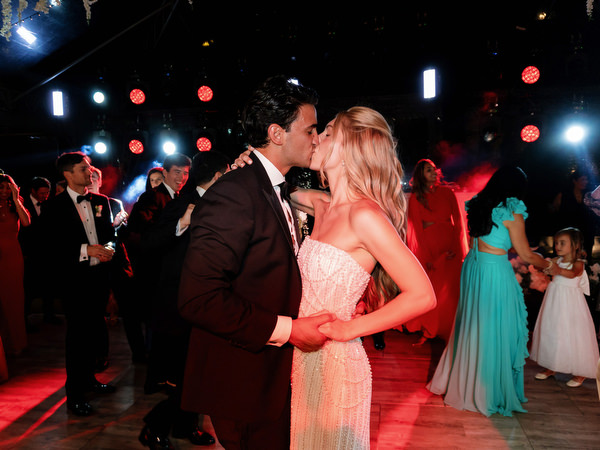 Bride and groom dancing closely under red stage lighting during late-night celebration