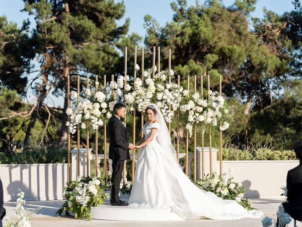 Bride and groom standing beneath floral arch during Athens wedding